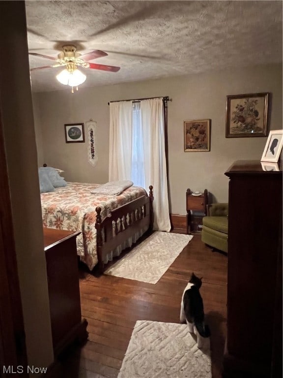 bedroom with a textured ceiling, ceiling fan, and hardwood / wood-style floors