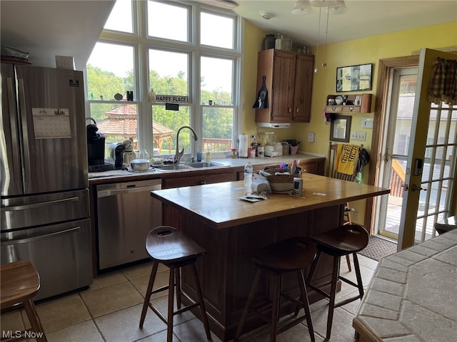 kitchen featuring sink, a kitchen breakfast bar, stainless steel appliances, and light tile patterned floors