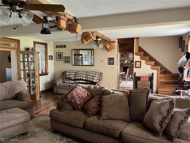 living room with hardwood / wood-style flooring, a textured ceiling, and ceiling fan