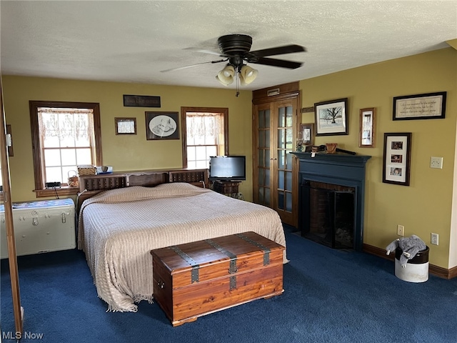 bedroom featuring multiple windows, a textured ceiling, ceiling fan, and carpet flooring