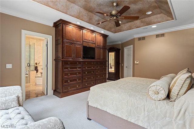 bedroom with ornamental molding, ensuite bath, ceiling fan, carpet flooring, and a tray ceiling