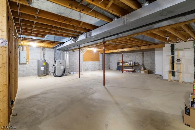 basement featuring electric water heater, electric panel, and heating unit