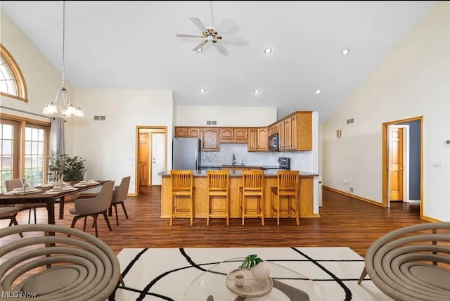 kitchen with high vaulted ceiling, decorative backsplash, dark wood-type flooring, and appliances with stainless steel finishes