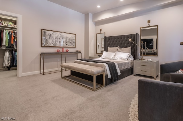 bedroom featuring a walk in closet, a closet, and light colored carpet