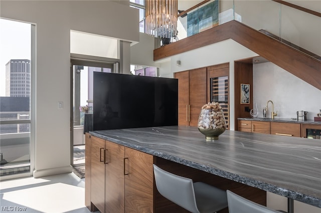 kitchen with a chandelier, a high ceiling, sink, dark stone counters, and a breakfast bar