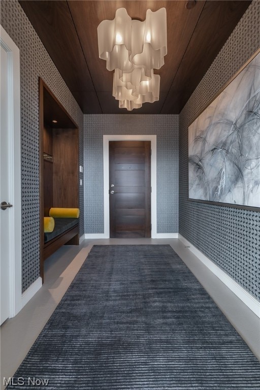 entrance foyer with carpet floors, wood ceiling, and a notable chandelier