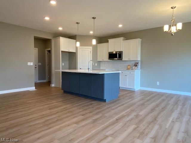 kitchen featuring white cabinets, light hardwood / wood-style floors, and decorative light fixtures