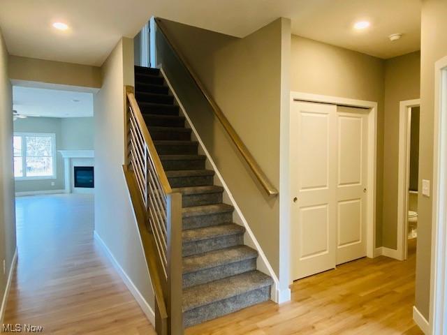 stairs featuring ceiling fan and hardwood / wood-style flooring