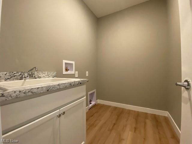 laundry area featuring sink, cabinets, hookup for a washing machine, and light hardwood / wood-style flooring