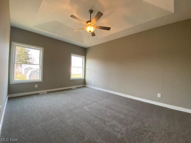 carpeted spare room featuring ceiling fan and a tray ceiling