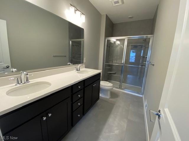 bathroom with toilet, tile patterned flooring, a shower with shower door, and vanity