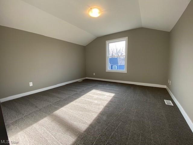 bonus room featuring dark carpet and vaulted ceiling