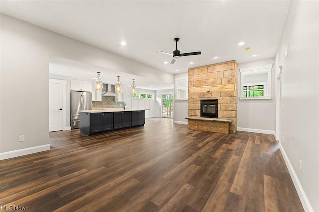 unfurnished living room featuring plenty of natural light, ceiling fan, and dark hardwood / wood-style floors