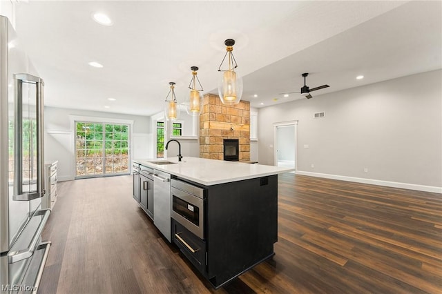 kitchen featuring ceiling fan, sink, hanging light fixtures, a kitchen island with sink, and appliances with stainless steel finishes