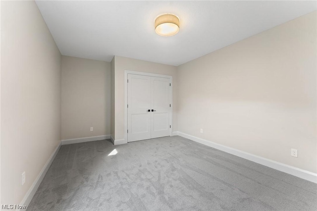 unfurnished bedroom featuring light carpet and a closet