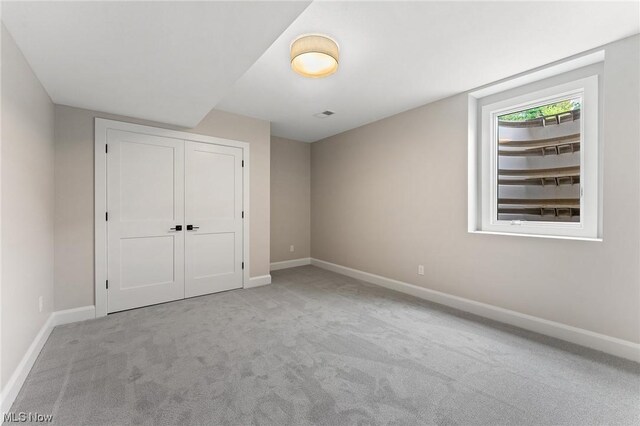 unfurnished bedroom with light carpet and a closet