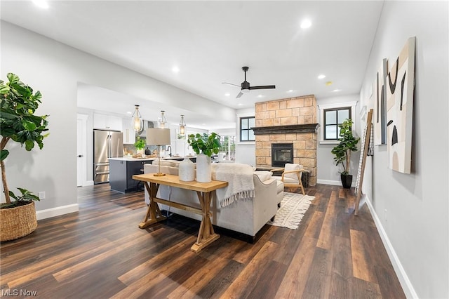 living room with a stone fireplace, ceiling fan, dark hardwood / wood-style flooring, and sink