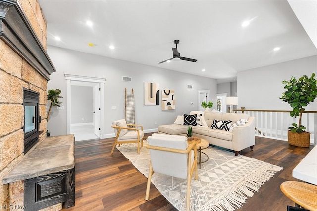 living room featuring dark hardwood / wood-style floors, ceiling fan, and a tiled fireplace