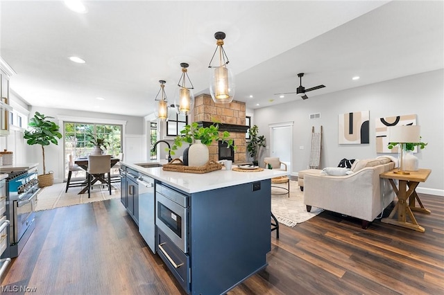 kitchen featuring a kitchen bar, sink, blue cabinetry, pendant lighting, and a center island with sink