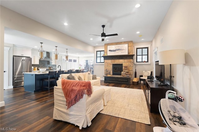 living room featuring sink, ceiling fan, dark hardwood / wood-style flooring, and a fireplace