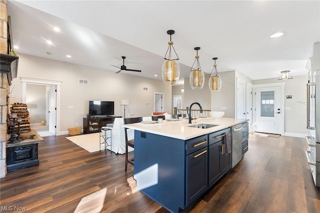 kitchen with blue cabinetry, sink, a kitchen breakfast bar, decorative light fixtures, and a center island with sink