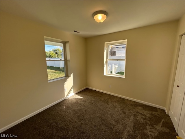 unfurnished bedroom with dark carpet and a closet