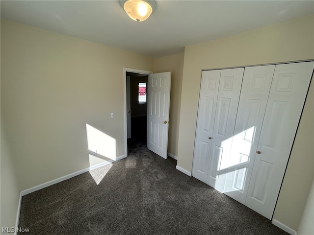 unfurnished bedroom with a closet and dark colored carpet