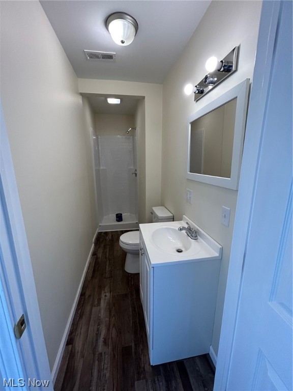 bathroom featuring vanity, toilet, a tile shower, and hardwood / wood-style flooring