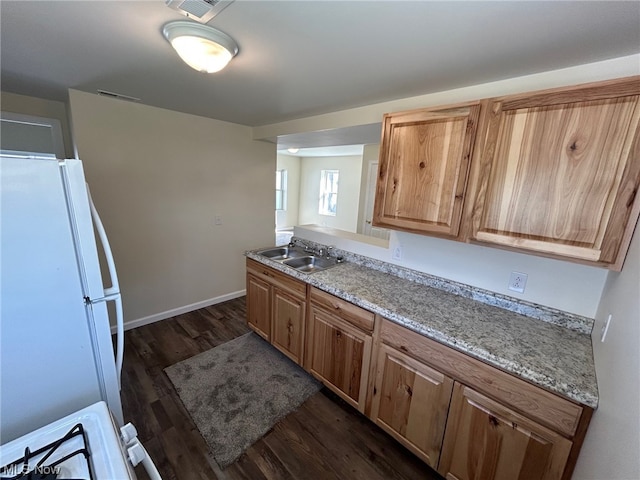 kitchen with sink, dark hardwood / wood-style flooring, white refrigerator, and light stone counters