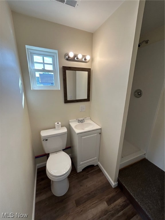 bathroom with a shower, vanity, wood-type flooring, and toilet