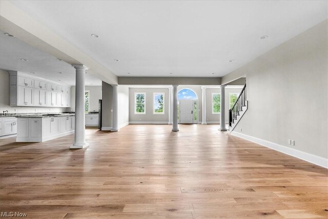2585 Glendale Rd, Marietta, OH 45750 - unfurnished living room with light wood-style flooring, a healthy amount of sunlight, baseboards, and ornate columns