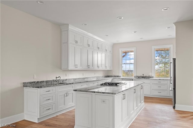 2585 Glendale Rd, Marietta, OH 45750 - kitchen featuring a center island, light stone counters, light wood-style floors, white cabinetry, and a sink