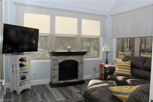 living room featuring a stone fireplace, vaulted ceiling, and hardwood / wood-style flooring