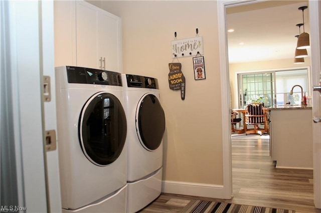 clothes washing area with independent washer and dryer, cabinets, and light hardwood / wood-style floors