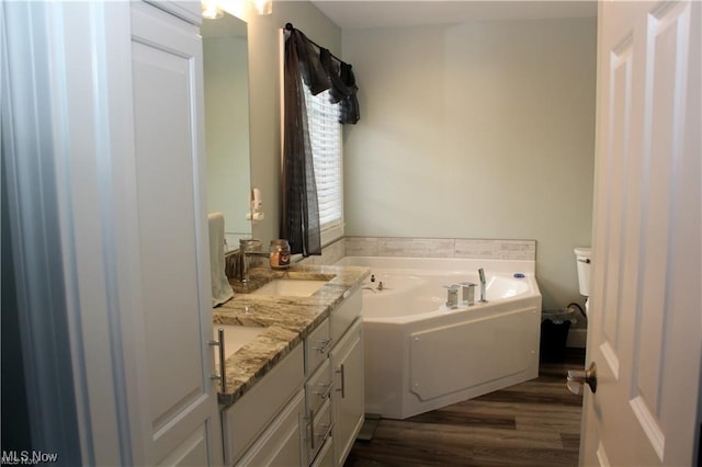 bathroom with hardwood / wood-style flooring, vanity, a tub, and toilet