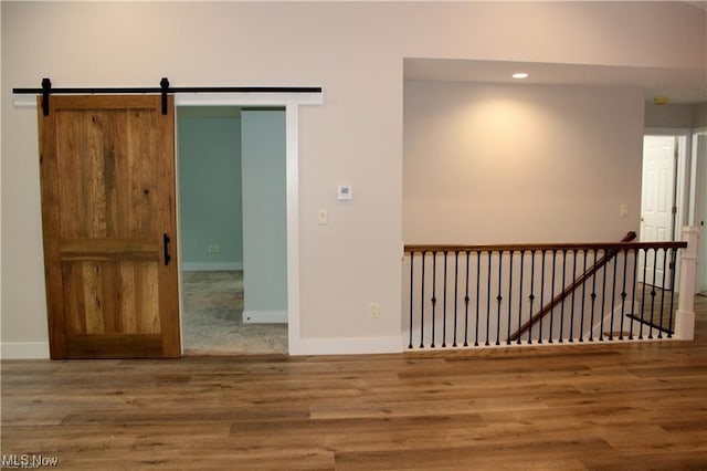 spare room featuring wood-type flooring and a barn door