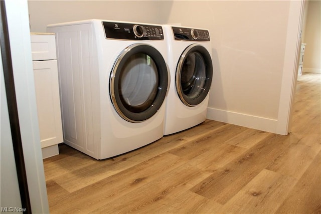 laundry room featuring washing machine and clothes dryer and light hardwood / wood-style floors