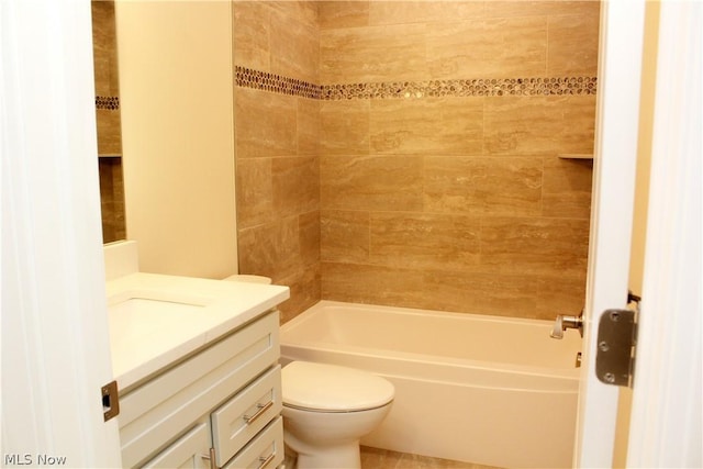 full bathroom featuring tiled shower / bath, vanity, and toilet