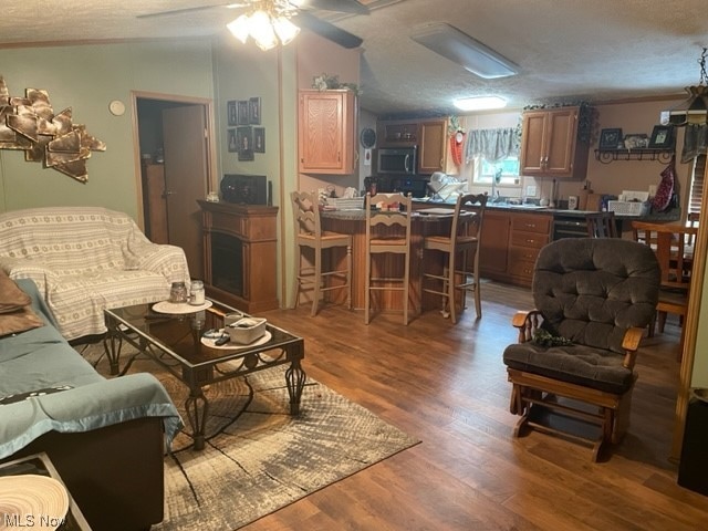 living room with a textured ceiling, ornamental molding, wood-type flooring, and ceiling fan