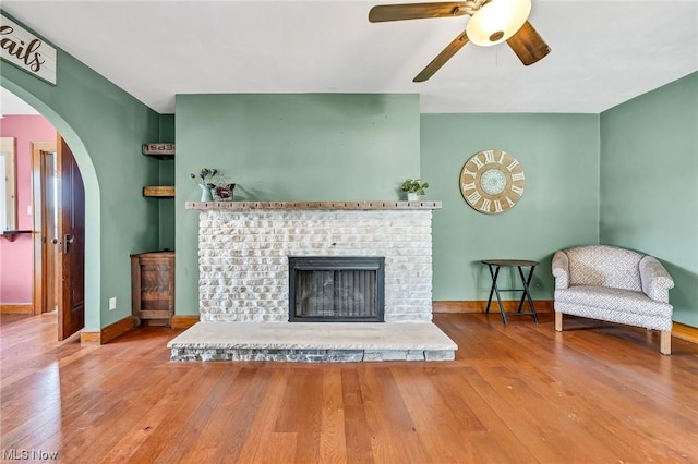 living room featuring hardwood / wood-style flooring, ceiling fan, and a fireplace