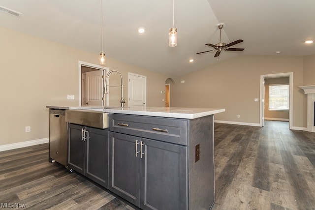 kitchen featuring an island with sink, pendant lighting, stainless steel dishwasher, ceiling fan, and dark wood-type flooring