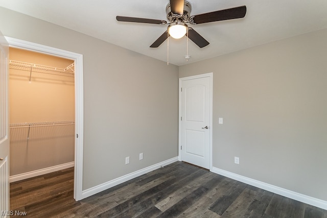 unfurnished bedroom featuring a spacious closet, a closet, ceiling fan, and dark hardwood / wood-style floors