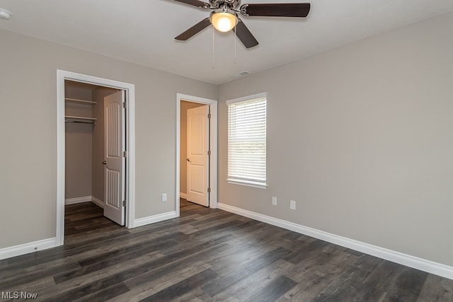 unfurnished bedroom with a closet, dark hardwood / wood-style floors, ceiling fan, and a walk in closet