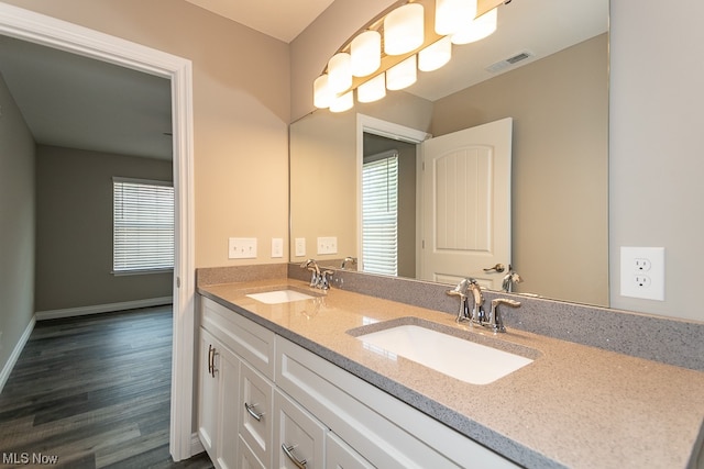 bathroom with dual sinks, hardwood / wood-style flooring, and vanity with extensive cabinet space