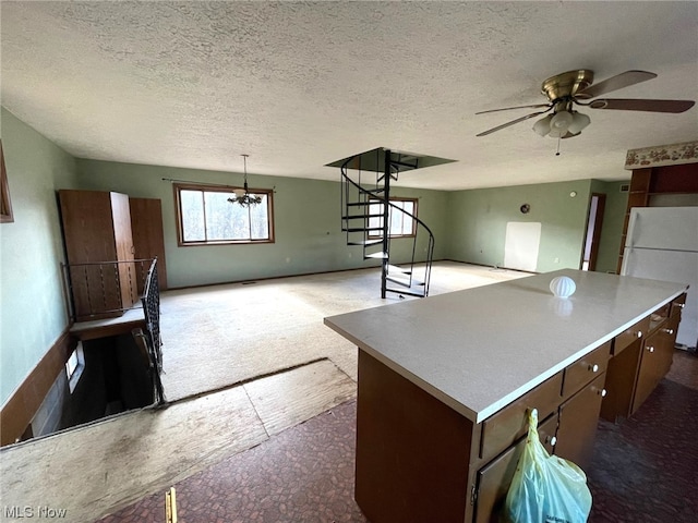 kitchen with carpet flooring, white fridge, dark brown cabinets, a kitchen island, and ceiling fan