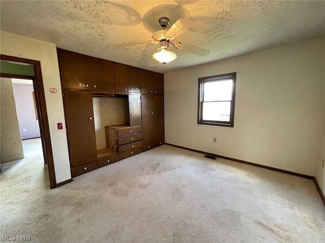 unfurnished bedroom featuring a textured ceiling, light colored carpet, a closet, and ceiling fan