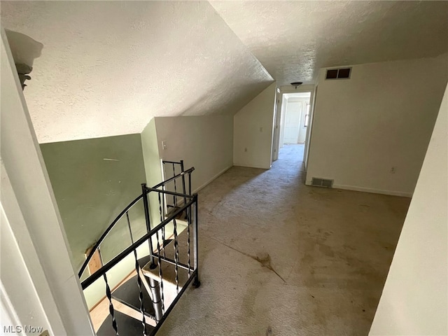 additional living space featuring a textured ceiling and lofted ceiling