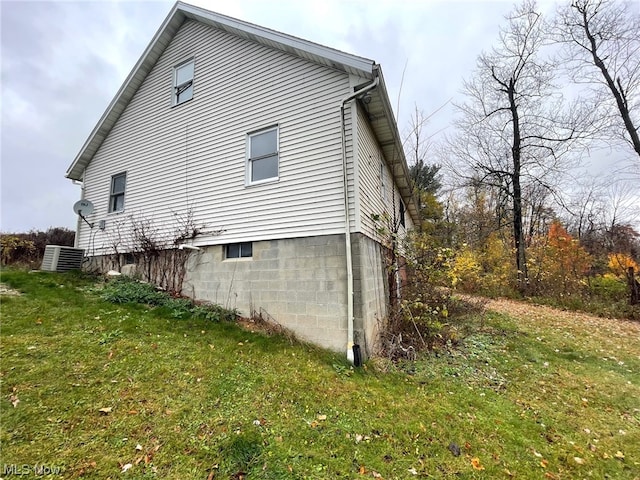 view of side of home featuring a yard and central AC