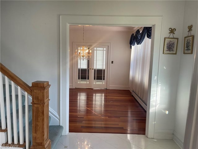 hallway featuring tile patterned floors, french doors, an inviting chandelier, and a baseboard heating unit