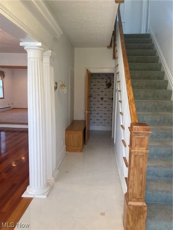 stairs with decorative columns and a baseboard radiator